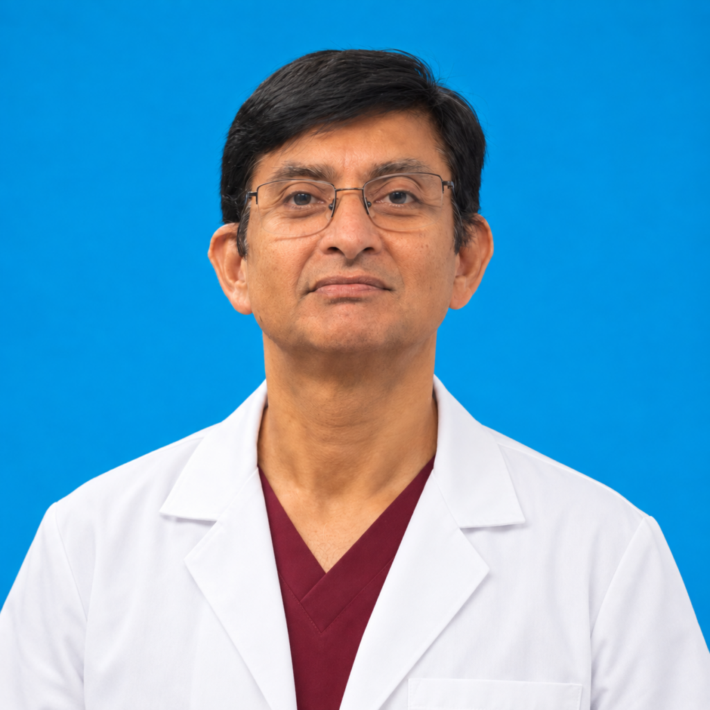 A man with short dark hair and glasses wears a white lab coat over a maroon shirt, standing against a plain blue background.